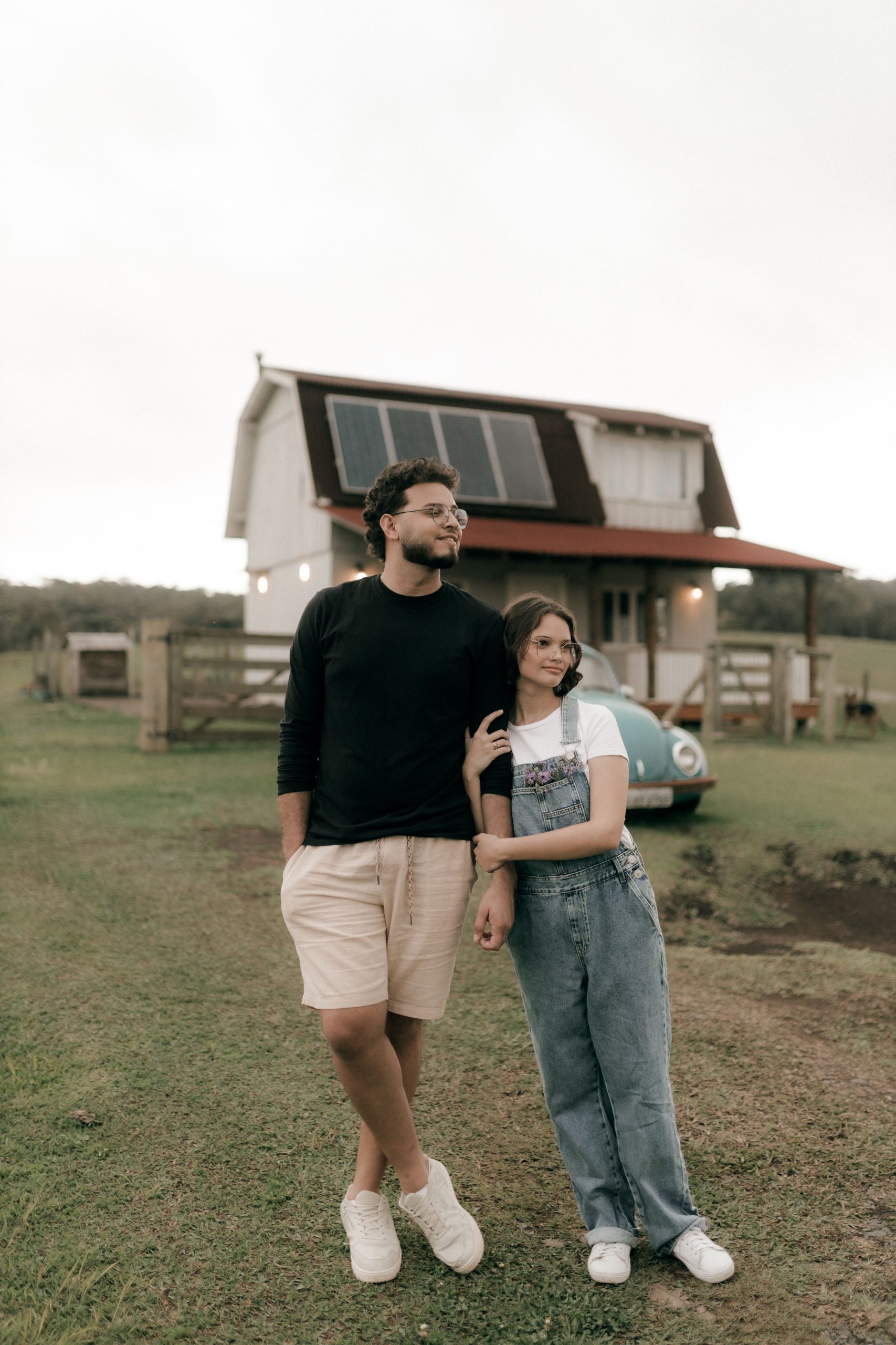 A young couple enjoying their time outdoors by a modern barn house on a cloudy day.